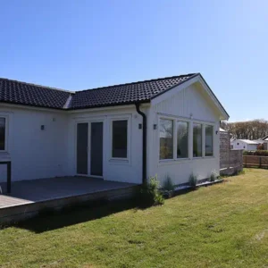 Vit villa i Varberg med nytt ljust uterum och energieffektiva fönsterpartier ut mot altanen.