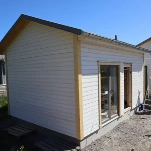 Ett nybyggt Attefallshus med vit träpanel och glasdörrar under uppbyggnad i Varberg.