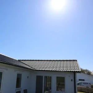 Vit villa i Varberg med ett nytt, tätt och stilrent tak av svarta takpannor.