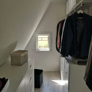 Nyrenoverad klädkammare med ljusa ytskikt och smart förvaring under snedtak i en bostad i Varberg.
