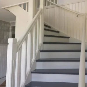 Nyrenoverad vit och grå trätrappa med klassisk träpanel, ett exempel på våra snickeriarbeten.