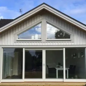 Husgavel med specialanpassade trekantiga fönster och moderna skjutdörrar i glas för ett inglasat uterum.