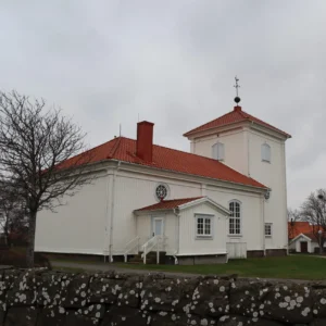 Vit träbyggnad i Varberg med ett vackert och nylagt rött tegeltak.